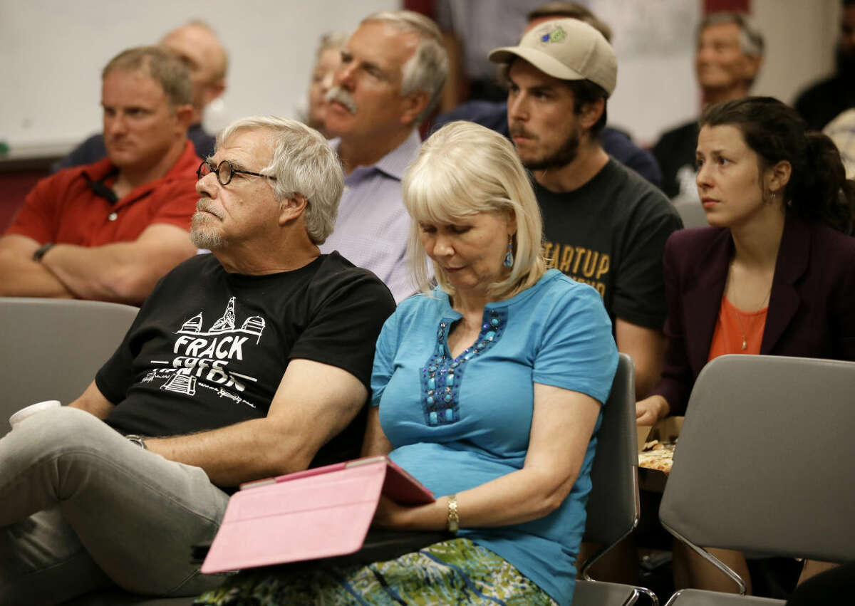 Area residents and registered speakers watch proceedings on a television screen from one of the three overflow rooms as others wait their turn to address the city council during a public hearing, Tuesday, July 15, 2014, in Denton, Texas. The North Texas city could become the first in the state to ban hydraulic fracturing if city leaders approve a citizen-led petition to outlaw the drilling method. (AP Photo/Tony Gutierrez)