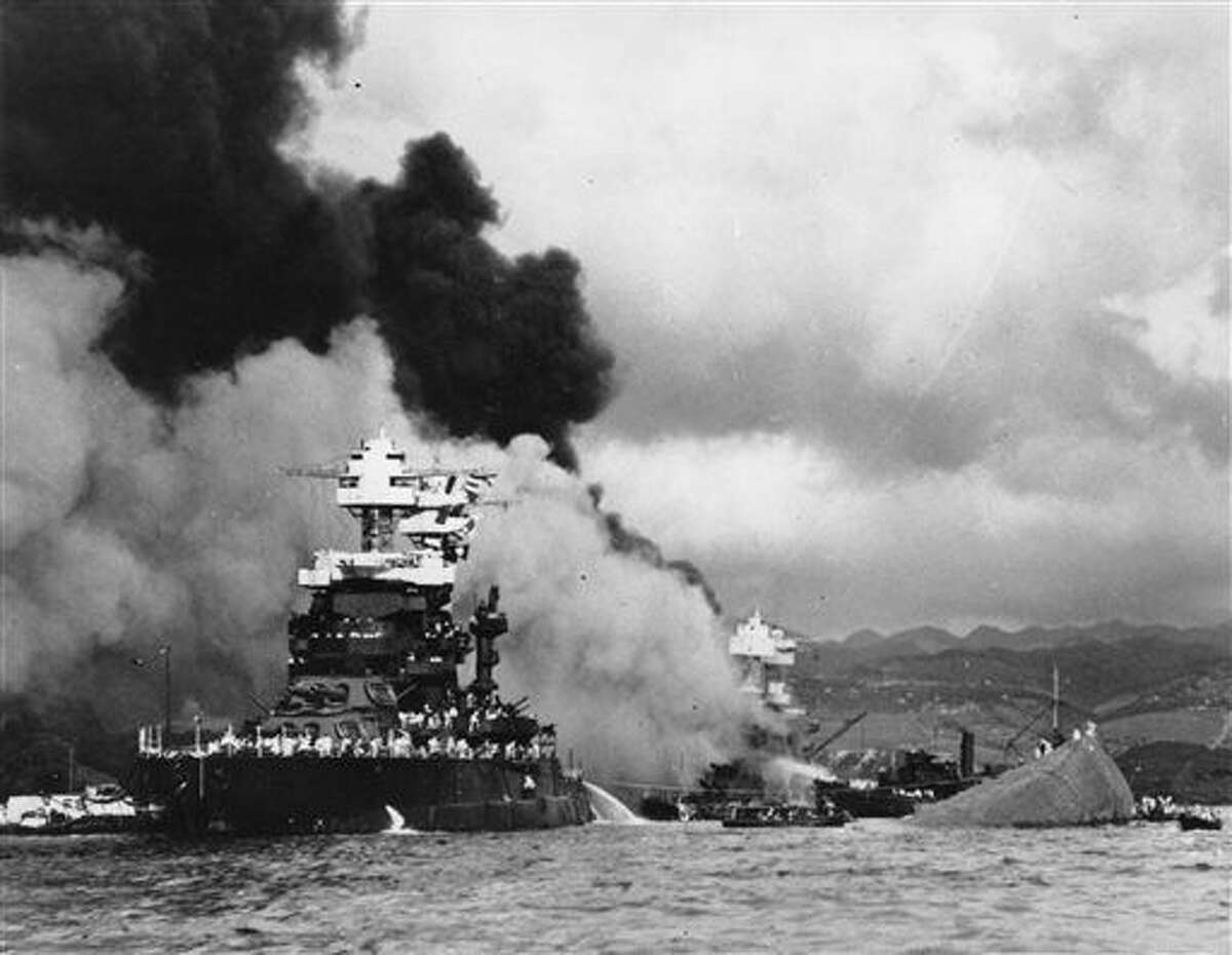 FILE - In this Dec. 7, 1941 file photo, part of the hull of the capsized USS Oklahoma is seen at right as the battleship USS West Virginia, center, begins to sink after suffering heavy damage, while the USS Maryland, left, is still afloat in Pearl Harbor, Oahu, Hawaii. A sailor killed in the attack on Pearl Harbor is being buried with full military honors nearly 75 years after the bombing. Machinist's Mate 1st Class Vernon Luke of Green Bay, Wisconsin is being buried at a veterans cemetery in Honolulu on Wednesday, March 9, 2016. (U.S. Navy via AP, File