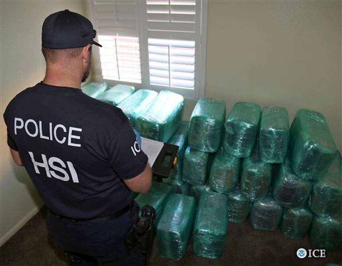 This photo provided by U.S. Immigration and Customs Enforcement shows an investigator Wednesday, March 23, 2016, viewing bags of marijuana stored in a room of a newly-built home in Calexico, Calif., the terminus of a cross-border tunnel that runs the length of four football fields to a restaurant in Mexicali, Mexico. An investigation netted more than a ton of marijuana and resulted in multiple arrests. It was the 12th completed secret passage that U.S. authorities have discovered along California’s border with Mexico since 2006. (U.S. Immigration and Customs Enforcement via AP) MANDATORY CREDIT