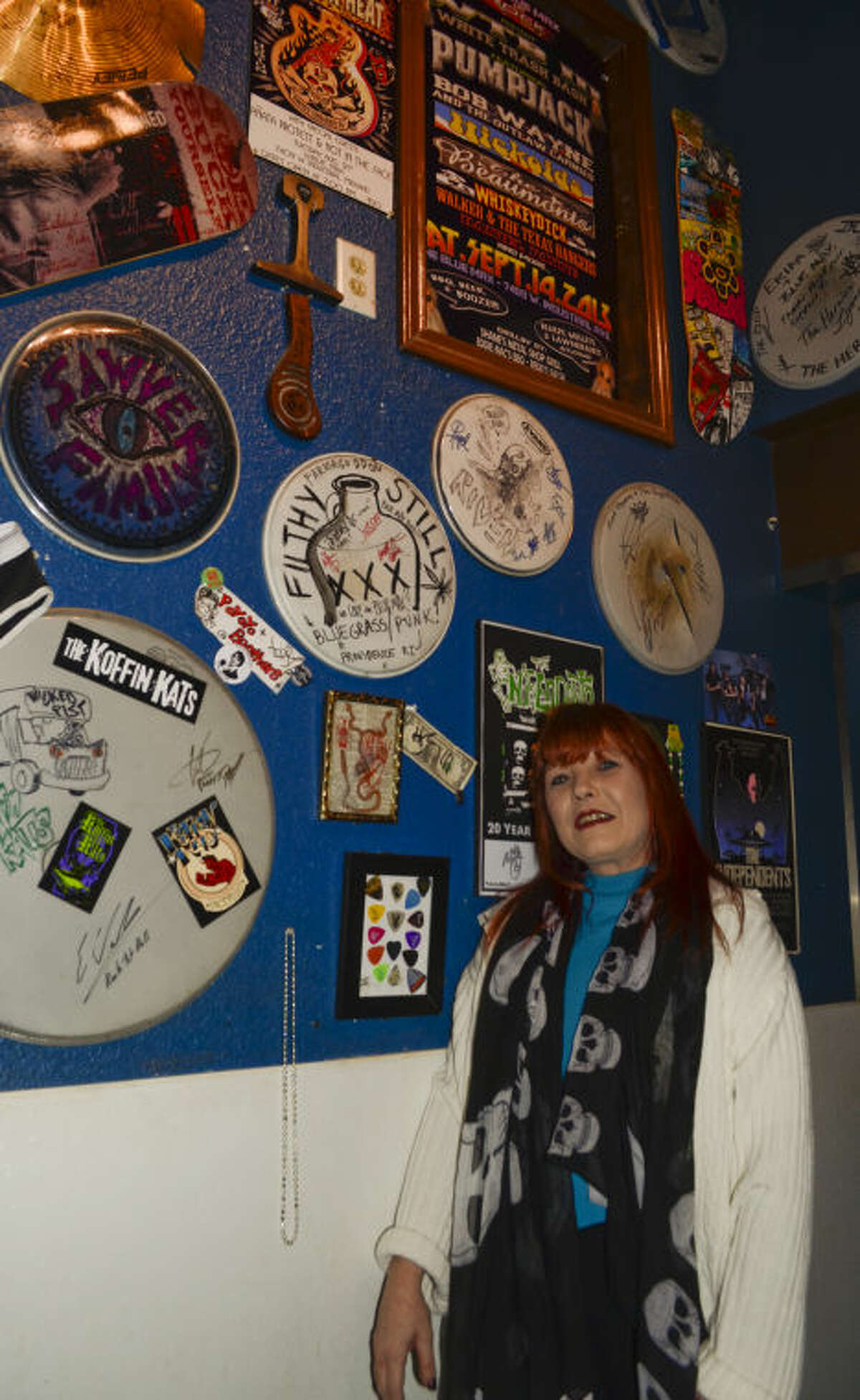 Erika Berry, owner of the Blue Max, stands next to a wall with mementoes from some of the bands that have played at the bar. Tim Fischer\Reporter-Telegram