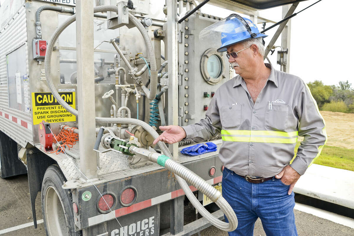 Linde truck driver, Howard Sanford, stands next to a portable refueling station for vehicles that operate on natural gas as opposed to gasoline, Tuesday afternoon outside of Uni-Trade Stadium during the South Central Texas Natural Gas Vehicle Consortium Meeting.