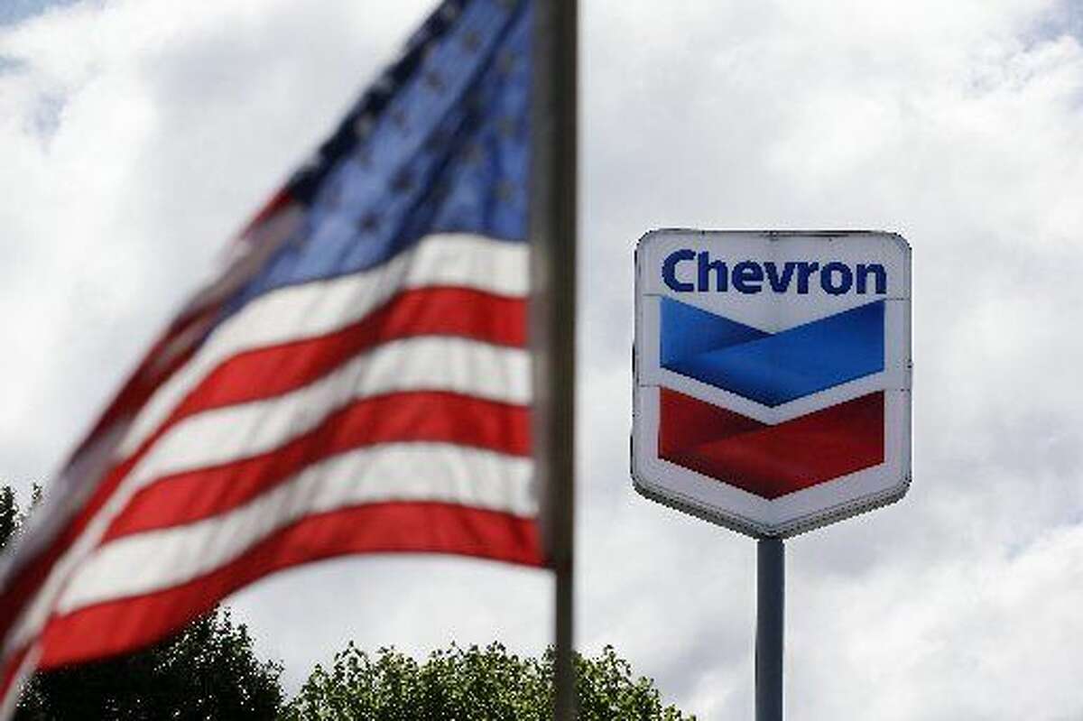 FILE - In this May 23, 2013, file photo, a United States flag flies in view of a Chevron gas station in Blaine, Wash. Chevron reports quarterly earnings on Friday, Jan. 31, 2014. (AP Photo/Elaine Thompson, File)