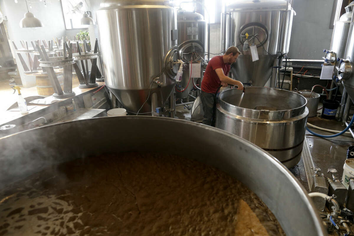 In this May 6, 2015 picture, Dan Winter, a brewer of the locally-owned Thorn Street Brewery cleans out a container as another heats during the beer making process in San Diego. New sweeping statewide cuts to urban water use approved this month are requiring Californians to reduce consumption between 8 percent and 36 percent from 2013 levels. (AP Photo/Gregory Bull)
