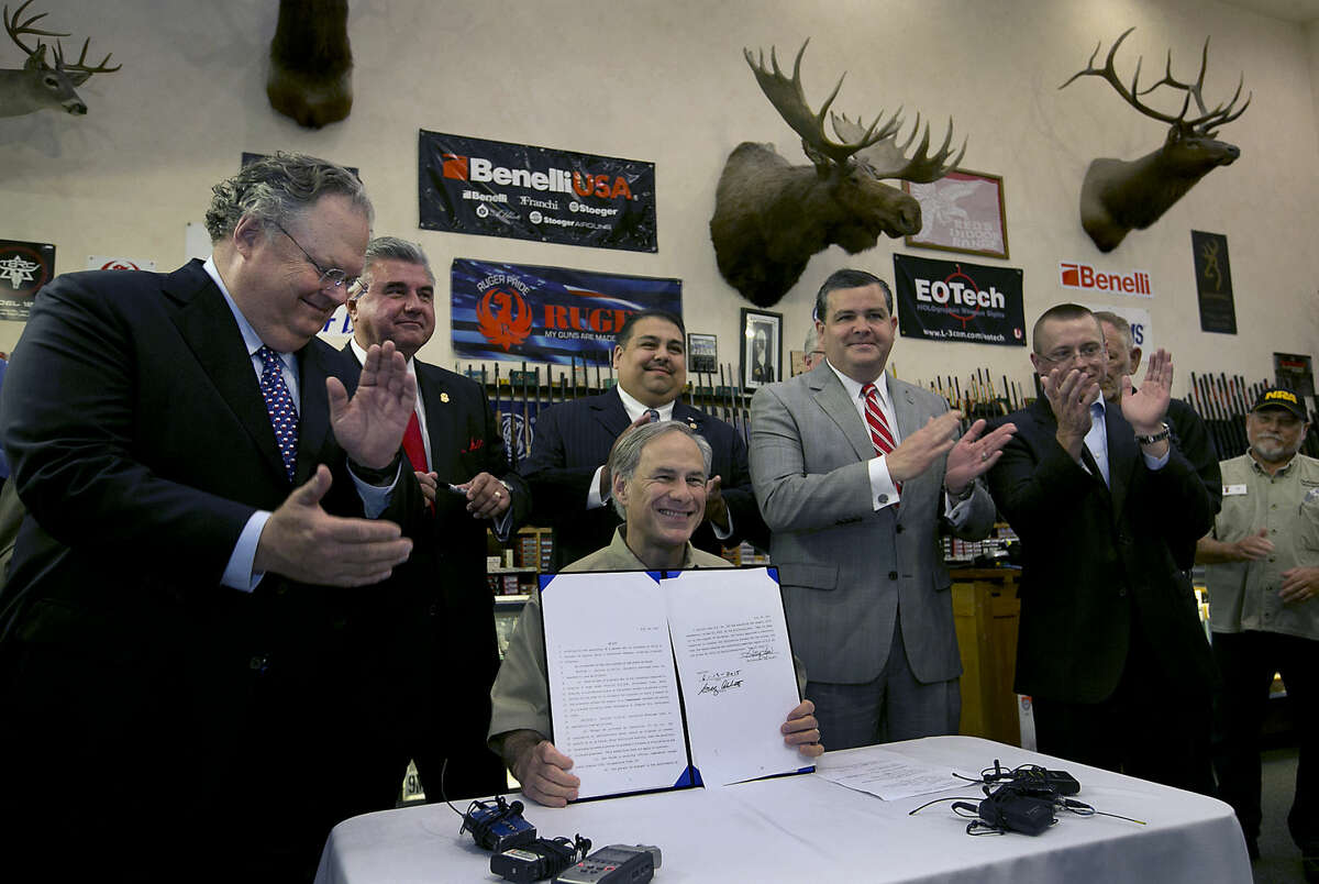 Texas Gov. Greg Abbott signs into law bills letting Texans carry concealed handguns on college campuses and openly carry them virtually everywhere else at Red's Indoor Range in Pfulgerville, Texas, Saturday, June 13, 2015. (Ralph Barrera/Austin American-Statesman via AP) AUSTIN CHRONICLE OUT, COMMUNITY IMPACT OUT, INTERNET AND TV MUST CREDIT PHOTOGRAPHER AND STATESMAN.COM, MAGS OUT