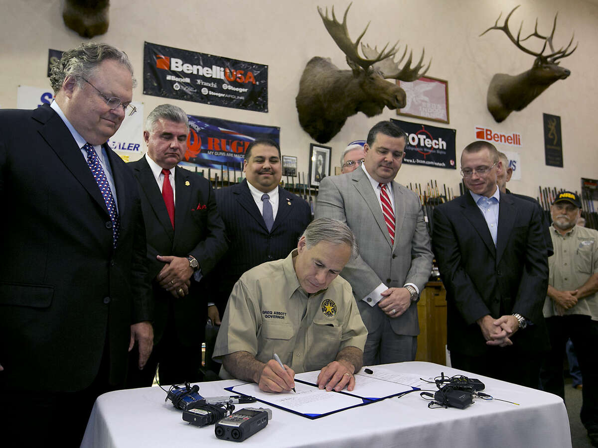 Texas Gov. Greg Abbott signs into law bills letting Texans carry concealed handguns on college campuses and openly carry them virtually everywhere else at Red's Indoor Range in Pfulgerville, Texas, Saturday, June 13, 2015. (Ralph Barrera/Austin American-Statesman via AP) AUSTIN CHRONICLE OUT, COMMUNITY IMPACT OUT, INTERNET AND TV MUST CREDIT PHOTOGRAPHER AND STATESMAN.COM, MAGS OUT