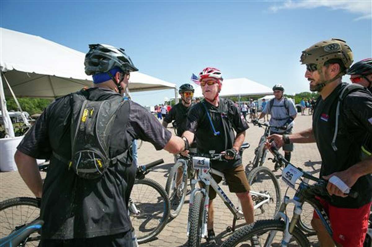 Former President George W. Bush greets participants during the second day of a three-day, 100-kilometer mountain bike ride with 16 wounded veterans Friday, May 2, 2014, in Crawford, Texas. (AP Photo/George W. Bush Presidential Center, Paul Morse)