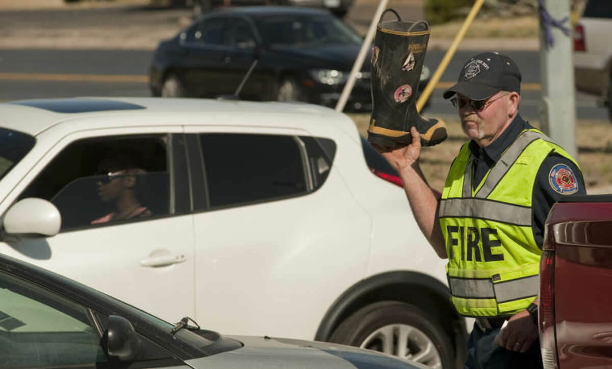 Midland Fire Department Driver Gary Wade carries his boot between cars Wednesday as the Midland Fire Department kicks off this years Fill the Boot campaign to raise money for Muscular Dystrophy. Tim Fischer\Reporter-Telegram