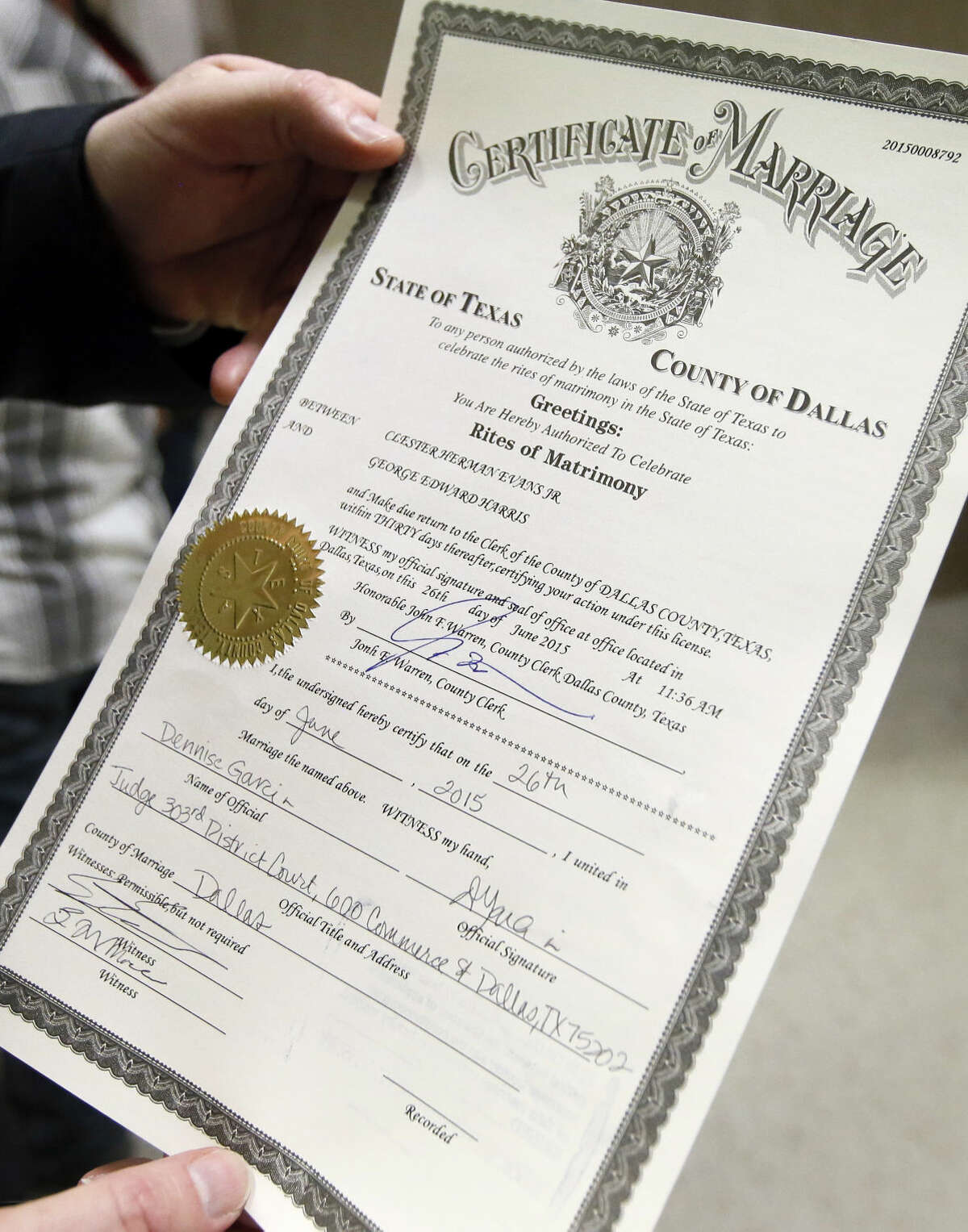 A friend of Jack Evans and George Harris holds the first marriage license issued to a same sex couple in Dallas County in Dallas on Friday, June 26, 2015. The couple of 54 years were married in a courtroom shortly after receiving the license. Friday's U.S. Supreme Court ruling legalizes gay marriage nationwide, including in the 14 remaining states with bans. (AP Photo/Tony Gutierrez)