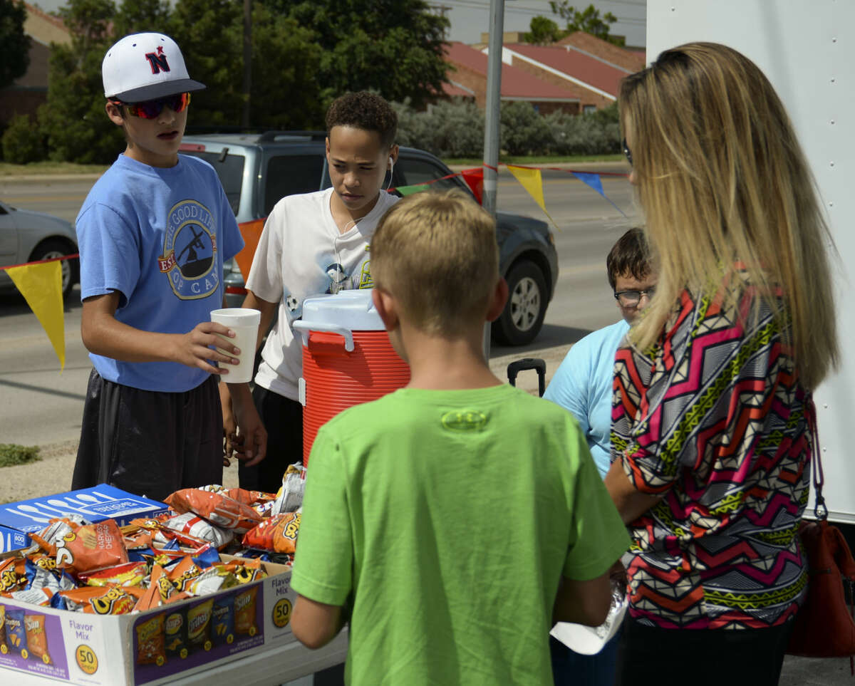 Jonathan Aguirre and others serve up freshmade lemonade to Stephanie Fife and her son Kyler Wednesday 7-8-15, as they and other junior high students hold a lemonade sale and car wash to raise money for Opportunity Camp. Tim Fischer\Reporter-Telegram