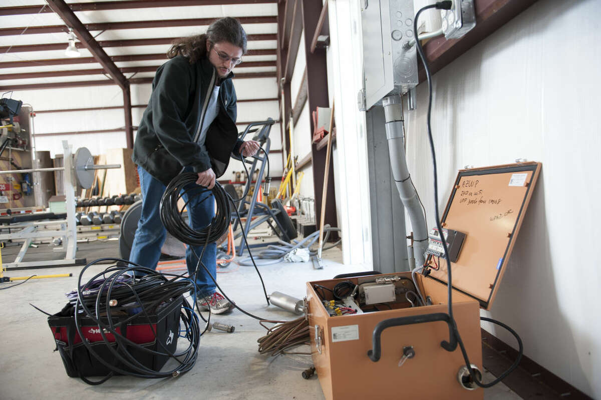 This handout photo, taken Jan. 16, 2014, provided by Southern Methodist University, shows Remi Oldham, an SMU geophysics graduate student, running a cable to connect the seismometer to communications interface equipment housed in the orange metal box in Willow Park, Texas. The interface equipment allows the transmission of the data collected by the seismometer back to SMU. With real-time monitors, scientists linked a swarm of small earthquakes west of Fort Worth, Texas, to nearby natural gas wells and wastewater injection. In 84 days from November 2013 to January 2014, the area around Azle, Texas, shook with 27 magnitude 2 or greater earthquakes, while scientists at Southern Methodist University and the U.S. Geological Survey monitored the shaking. It’s an area that had no recorded quakes for 150 years on faults that “have been inactive for hundreds of millions of years,” said SMU geophysicist Matthew Hornbach. (Hillsman Stuart Jackson/SMU via AP)