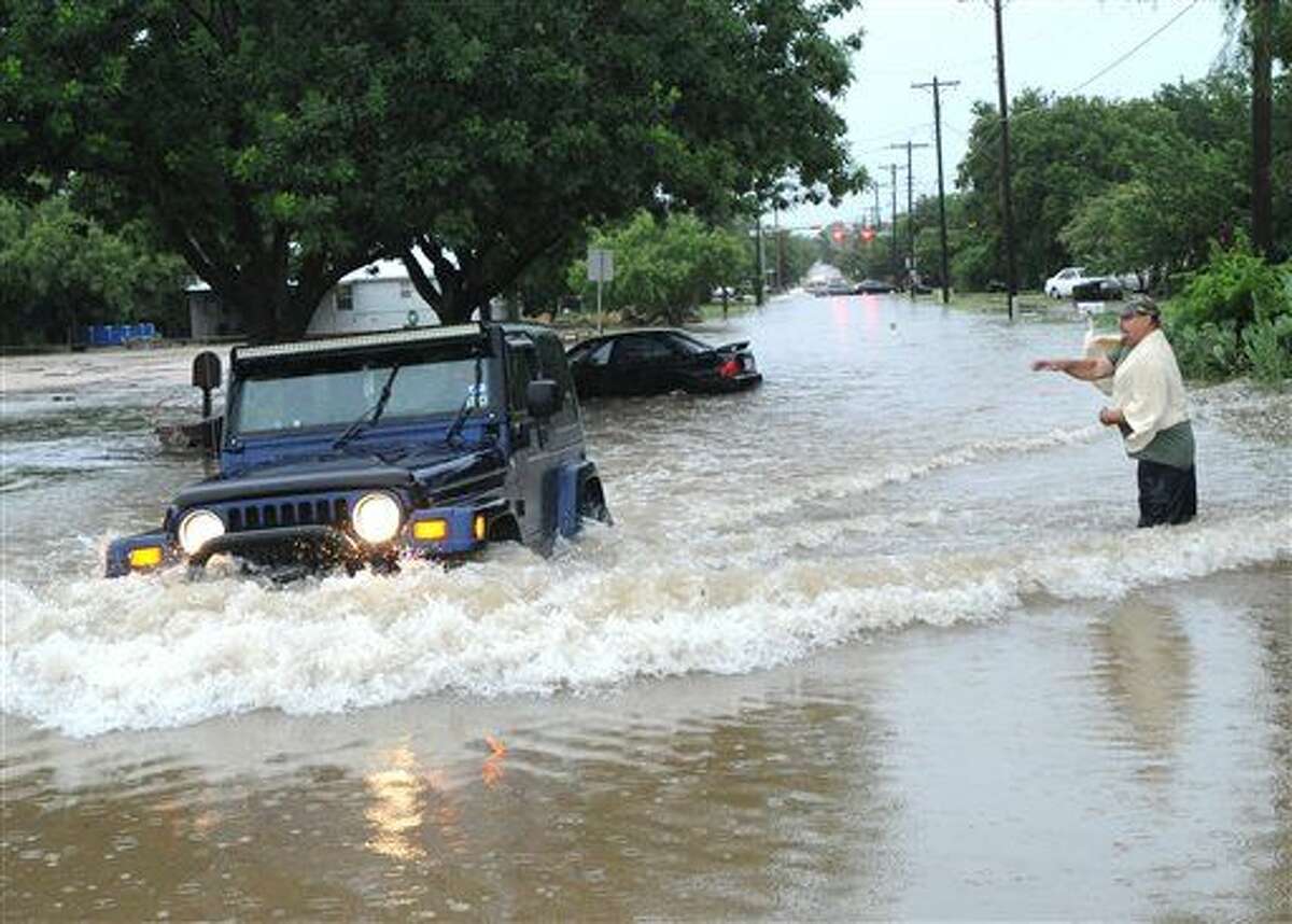 A homeowner throws a rock at a motorist driving through deep water on South 11th Street near Catclaw Creek, as the waves are lapping into the man's garage nearby Tuesday, July 7, 2015, in Abilene, Texas. (Nellie Doneva/The Abilene Reporter-News via AP)