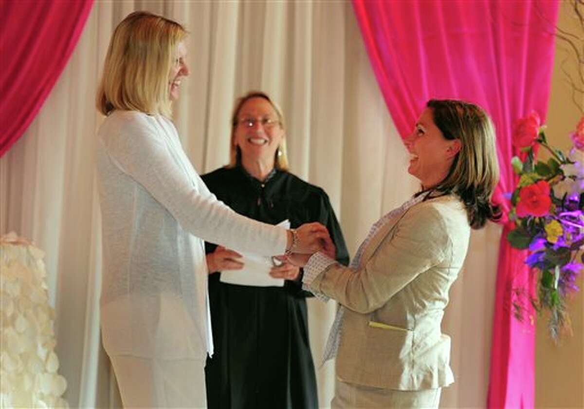 Julie Engbloom, left, and Laurie Brown, right, get married by Judge Beth A. Allen at the Melody Ballroom, Monday, May, 19, 2014, in Portland, Ore. Federal Judge Michael McShane released an opinion on Oregon's Marriage Equality lawsuit that grants gay and lesbian couples the freedom to marry in Oregon. (AP Photo/Steve Dykes)