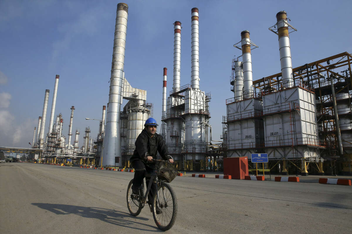 FILE - In this Dec. 22, 2014 file photo, an Iranian oil worker rides his bicycle at the Tehran's oil refinery south of the capital Tehran, Iran. Oil prices that slumped steeply earlier this year may take another hit once a historic deal between the West and Iran allows that country to start pouring more crude into a market already brimming with supply. (AP Photo/Vahid Salemi, File)