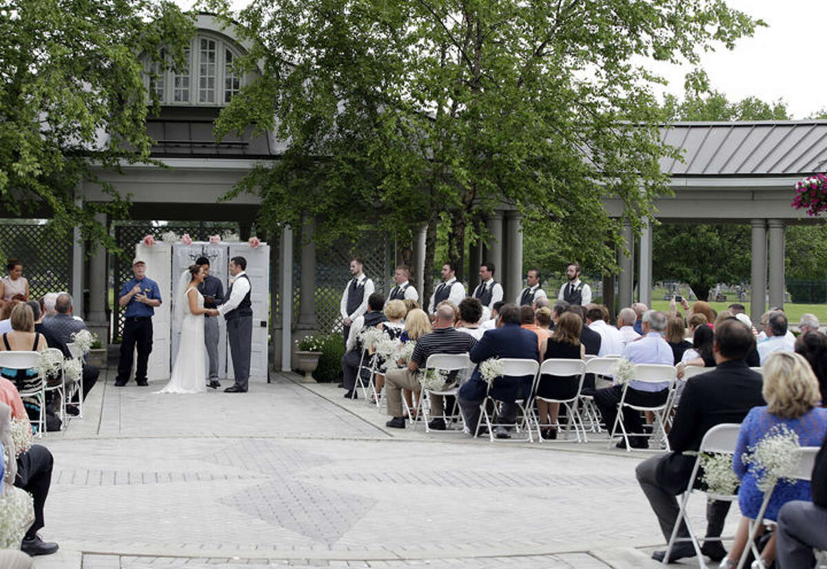 In this June 19, 2015 photo, Danessa Molinder and Billy Castrodale get married in the open air courtyard at the Community Life Center, in Indianapolis, which sits on cemetery land near a funeral home.