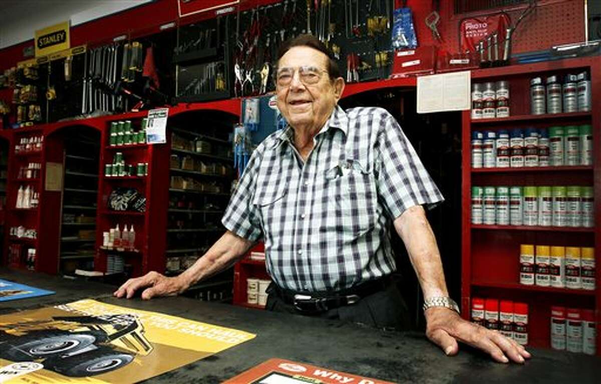In this photo taken on Tuesday, June 3, 2014, Edward Kalinowski, 97, smiles behind the counter at Victoria Bearing & Industrial Supply in Victoria, Texas. Kalinowski has been a part of the family business since he was just 13-years-old. He said Victoria Bearing & Industrial is still run as a family owned, local store. Their employees live locally, spend locally and are treated like family. He wants his employees to be happy an healthy at work. "I always tell them, it don't cost nothing to smile." he said. (AP Photo/The Victoria Advocate, Kathleen Duncan)