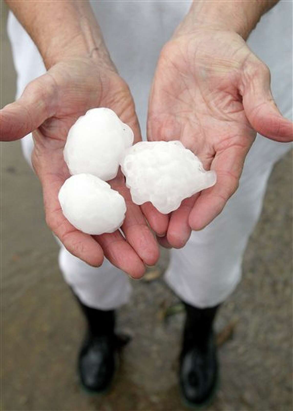 Melba Baker holds some of the golf ball plus size hail that fell at her home in Cunningham, Texas, Tuesday, April 3, 2012. Two large super cell thunderstorms brought heavy rain and damaging winds to North East Texas as well as tornadoes in the Dallas and Fort Woth area. (AP Photo/The Paris News, Sam Craft)