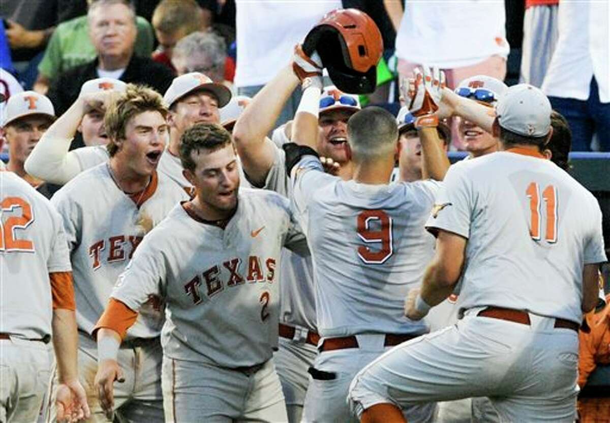Texas players greet C.J Hinojosa (9) to the dugout after he hit a home run against UC Irvine in the seventh inning of an NCAA baseball College World Series elimination game in Omaha, Neb., Wednesday, June 18, 2014. (AP Photo/Eric Francis)