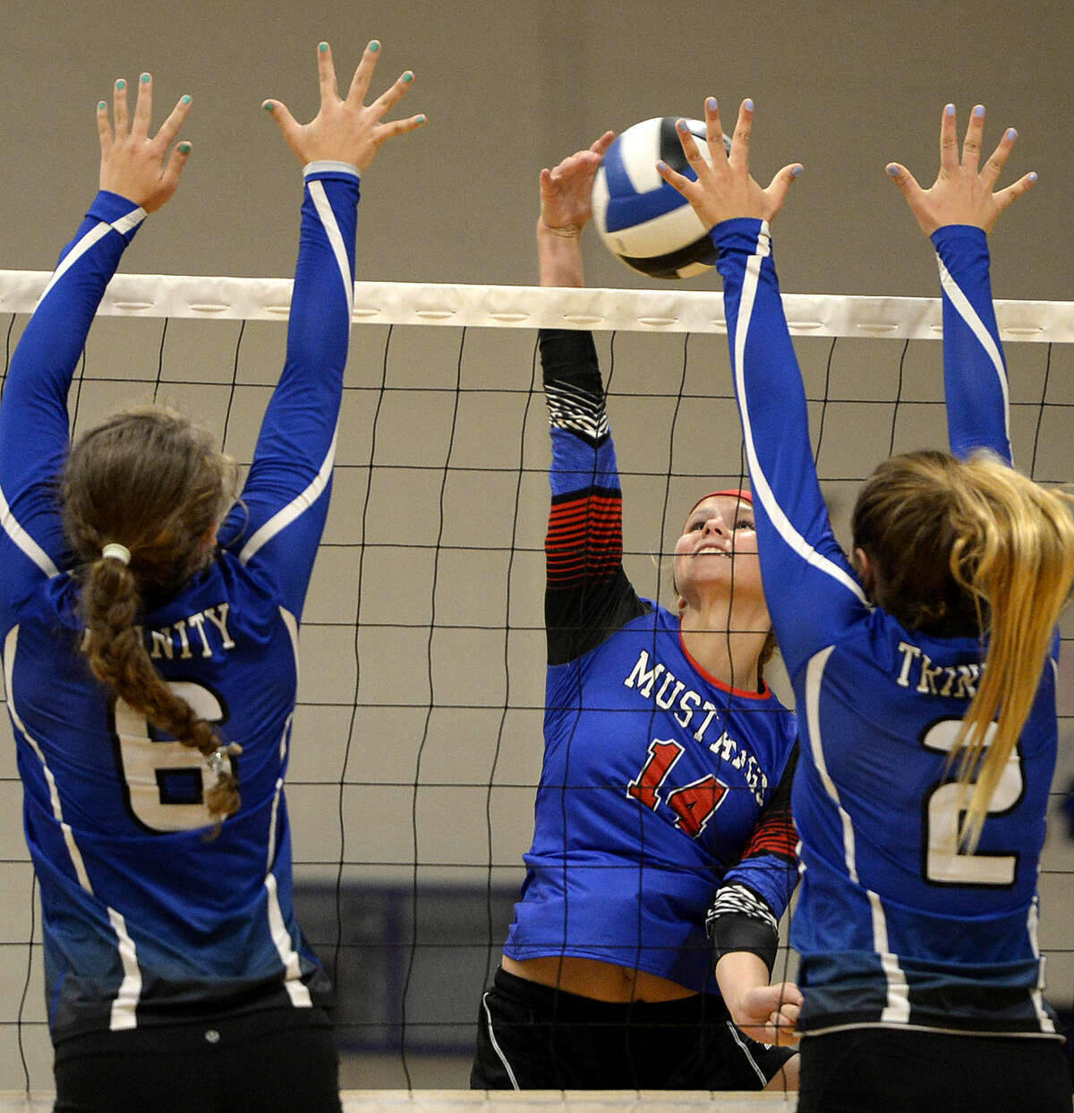 Midland Christian's Meagan Thomason (14) attempts to hit past Trinity's Mady Walker (6) and Carrie Herd (2) on Tuesday, August 11, 2015 at Beal Gymnasium. James Durbin/Reporter-Telegram