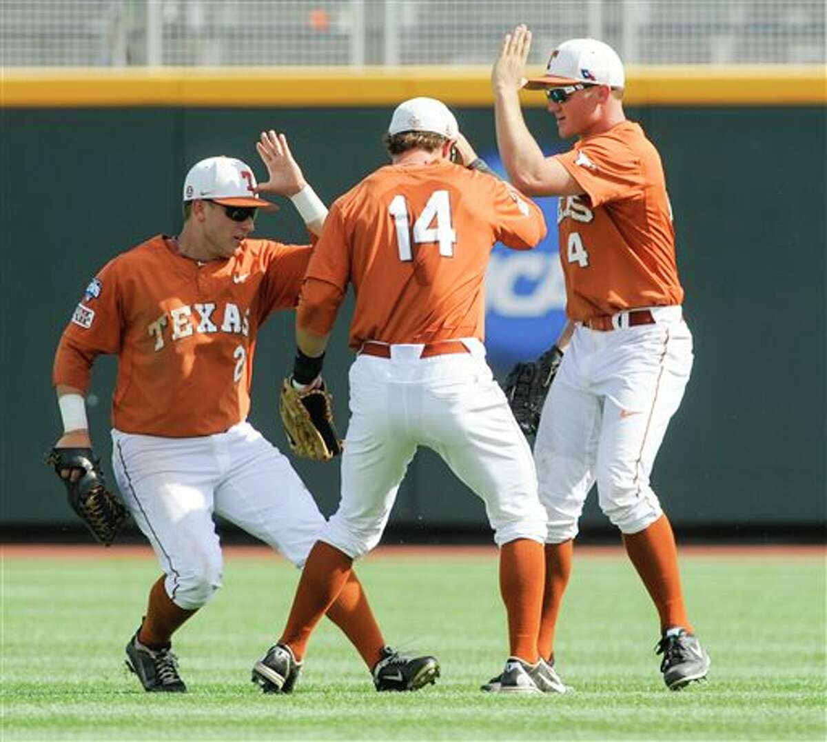 From left to right, Texas' Mark Payton, Ben Johnson and Collin Shaw celebrate after winning 4-0 against Vanderbilt in an NCAA baseball College World Series game in Omaha, Neb., Friday, June 20, 2014. (AP Photo/Eric Francis)