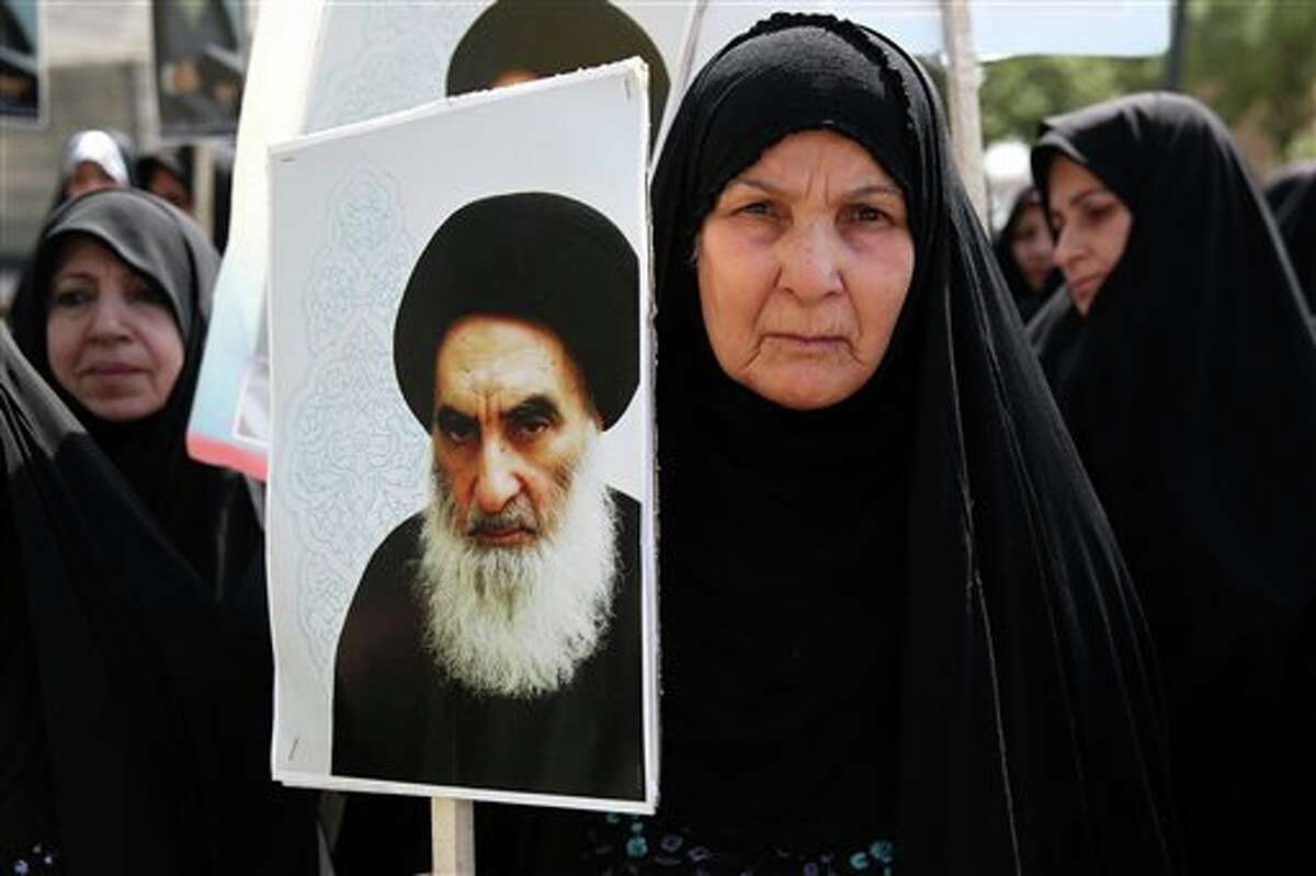 FILE - In this June 20, 2014 file photo, an Iraqi woman living in Iran holds a poster of the Grand Ayatollah Ali al-Sistani, Iraq's top Shiite cleric, in a demonstration against Sunni militants of the al-Qaida-inspired Islamic State of Iraq and the Levant, or ISIL, and to support Ayatollah al-Sistani, in Tehran, Iran. Prominent Shiite leaders pushed Thursday, June 26, 2014, for the removal of Iraqi Prime Minister Nouri al-Maliki as parliament prepared to start work next week on putting together a new government, under intense U.S. pressure to rapidly form a united front against an unrelenting Sunni insurgent onslaught. (AP Photo/Ebrahim Noroozi, File)