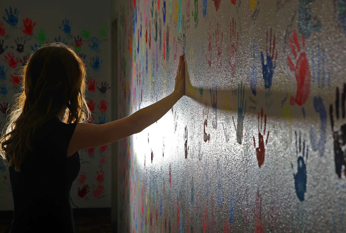 In this posed photo illustration, a model touches the handprints lining the walls of the Midland Rape Crisis and Children's Advocacy Center.