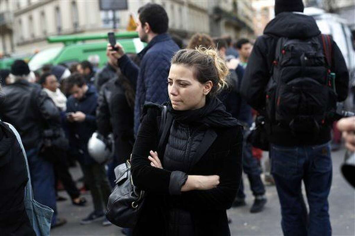 People react in front of the Carillon cafe and the Petit Cambodge restaurant in Paris Saturday Nov. 14, 2015, a day after over 120 people were killed in a series of shooting and explosions. (AP Photo/Jerome Delay)