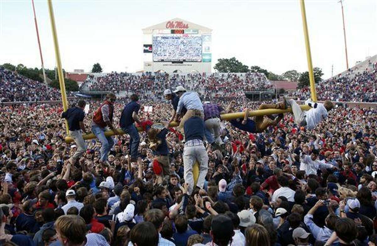 Mississippi fans gather on the field, as some clamber onto a goal post, after Mississippi defeated Alabama 23-17 in an NCAA college football game in Oxford, Miss., on Saturday Oct. 4, 2014. (AP Photo/Tuscaloosa News, Robert Sutton)