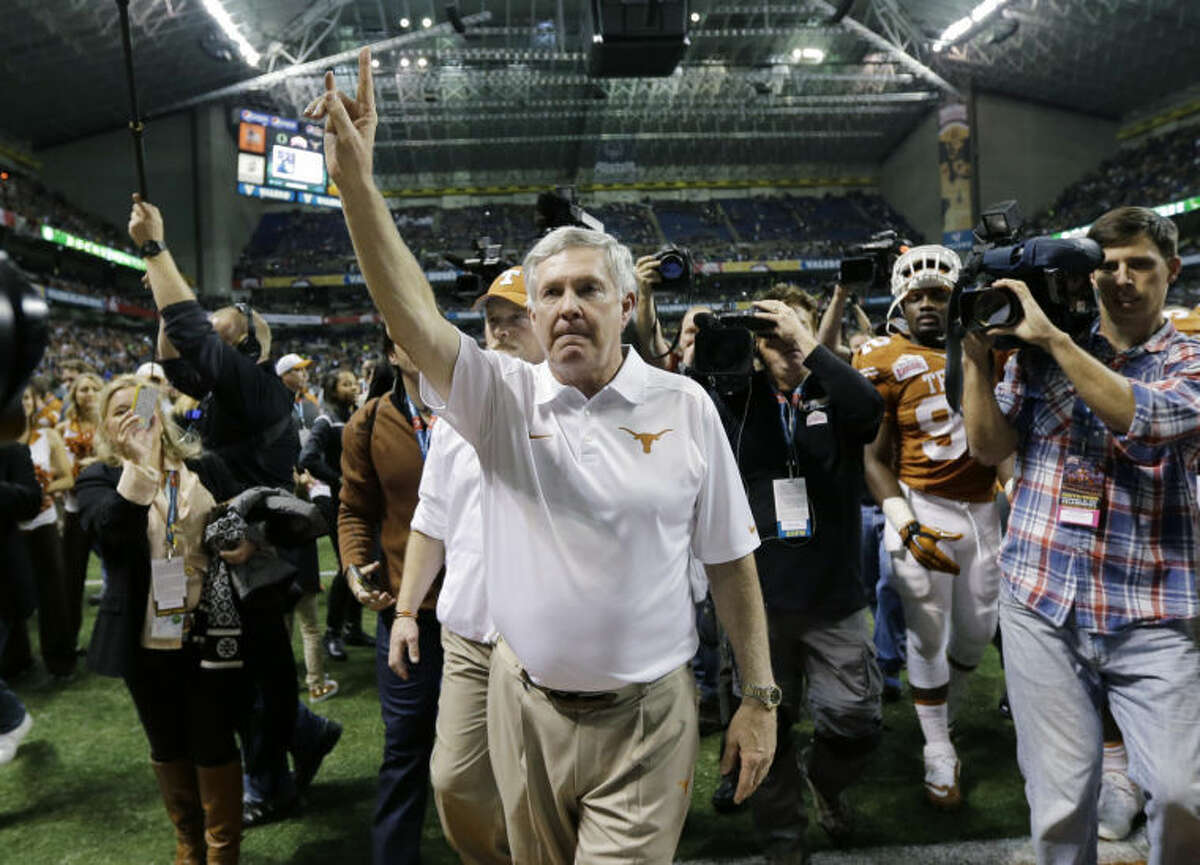 Texas coach Mack Brown, center, holds up the "Hook' em Horns" sign as he sings the school song following the Valero Alamo Bowl Monday, Dec. 30, 2013, in San Antonio. The man credited with the creation of the sign, Harley Clark, died Thursday. (AP Photo/Eric Gay)