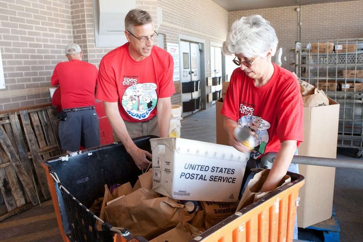 FILE - John Crooks, left, and Cindy Rice, with the West Texas Food Bank, sort through boxes of non-perishable items collected during the Stamp Out Hunger Food Drive, May 14 at the U.S. Post Office on Veterans Airpark Lane.  Cindeka Nealy/Reporter-Telegram