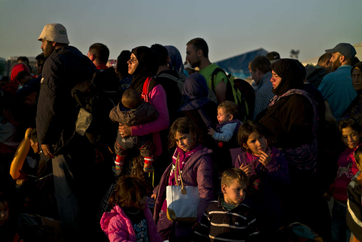 Syrian people line up to board a bus that will take them to the center for asylum seekers, after crossing the Serbian-Hungarian border near Roszke, southern Hungary, Saturday, Sept. 12, 2015. Hundreds of thousands of Syrian refugees and others are still making their way slowly across Europe, seeking shelter where they can, taking a bus or a train where one is available, walking where it isn't. (AP Photo/Muhammed Muheisen)