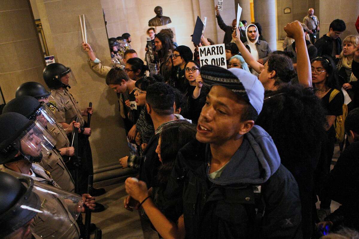 Protesters face off with San Francisco deputy sheriffs, after they stormed through the east side entrance of City Hall on Friday, May 6, 2016. Protesters entered the building after doors were locked blocking off the public from entering the building during a protest against SFPD and in support of the Frisco 5 hunger strikers in San Francisco. (AP Photo/Joel Angel Ju�rez)