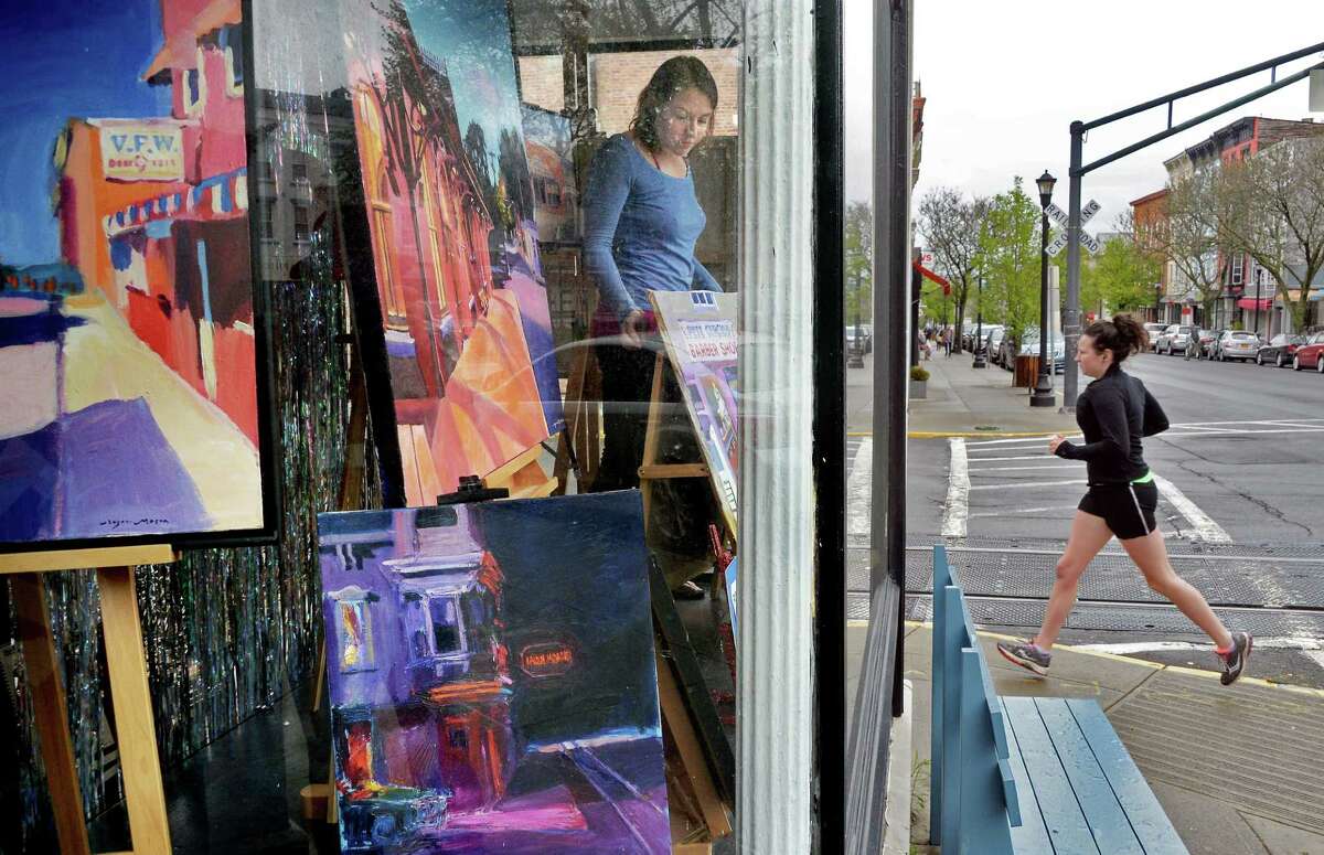 Amy Lavine, left, arranges paintings by New York artist Roger Mason in the window of her art supply and stationary shop, Sketch, on Warren Street Tuesday May 3, 2016 in Hudson , NY. (John Carl D'Annibale / Times Union)