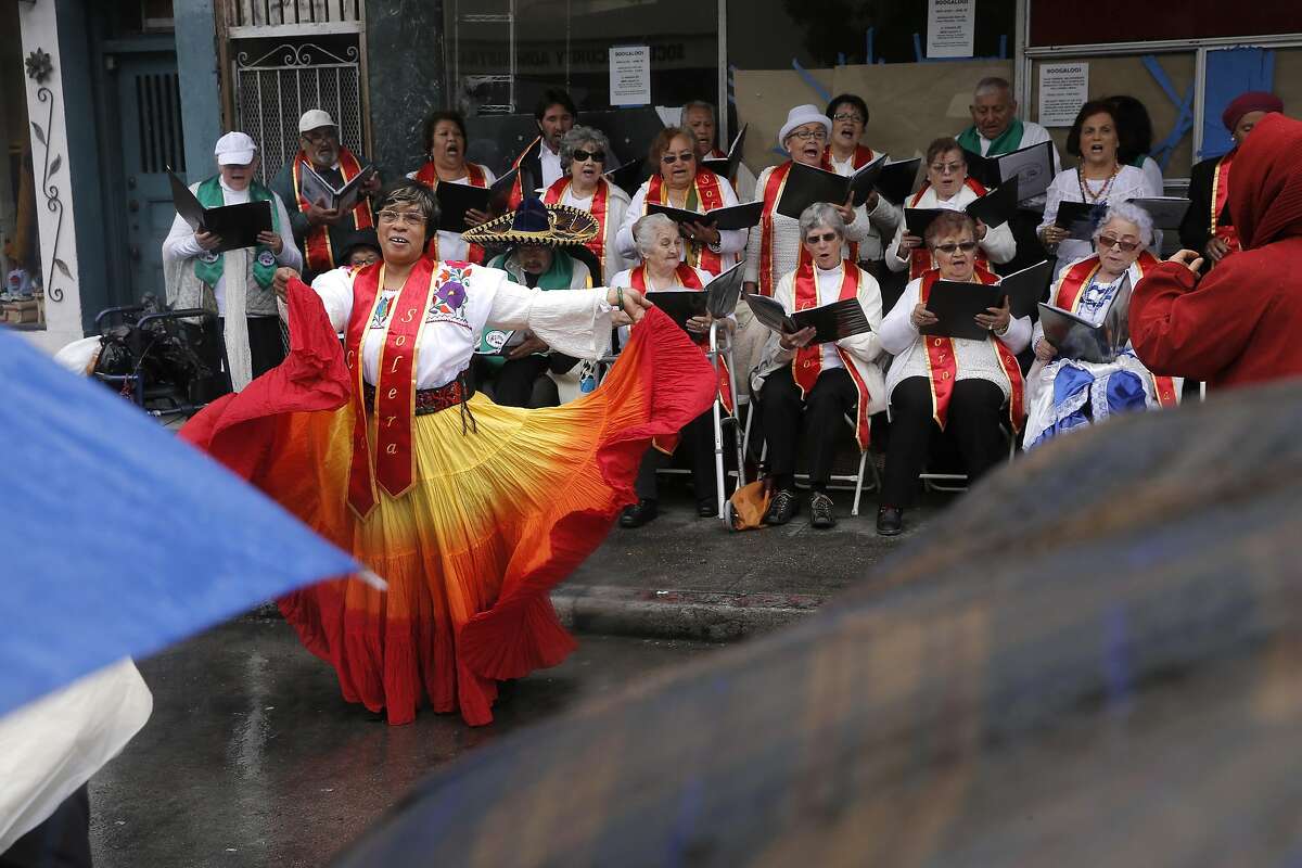 Christina Haynes dances with the adult choir from the Community Music Center of the Mission as they perform to a small audience during the Cinco de Mayo Festival despite the downpour of rain that put a dampen on the celebration along Valencia St. in the Mission neighborhood of San Francisco, California, on Sat. May 7, 2016. The Community Music Center's older adult choir is for those 55 years old and above with a desire to sing.