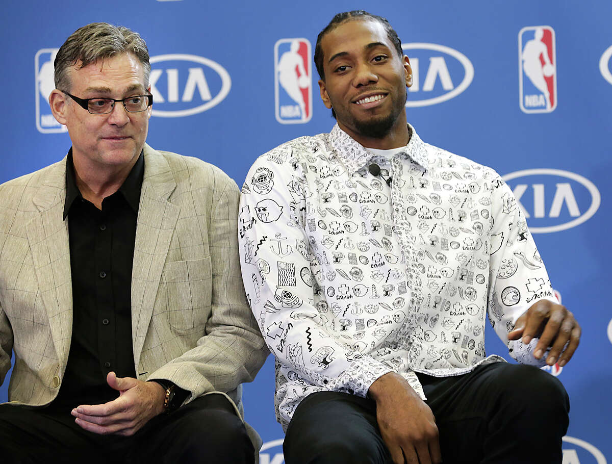 Kawhi Leonard, right, sits next to R. C. Buford, as he is presented the 2015-2016 NBA Defensive Player of the Year award on Monday, April 19, 2016, at the Spurs Practice Facility.