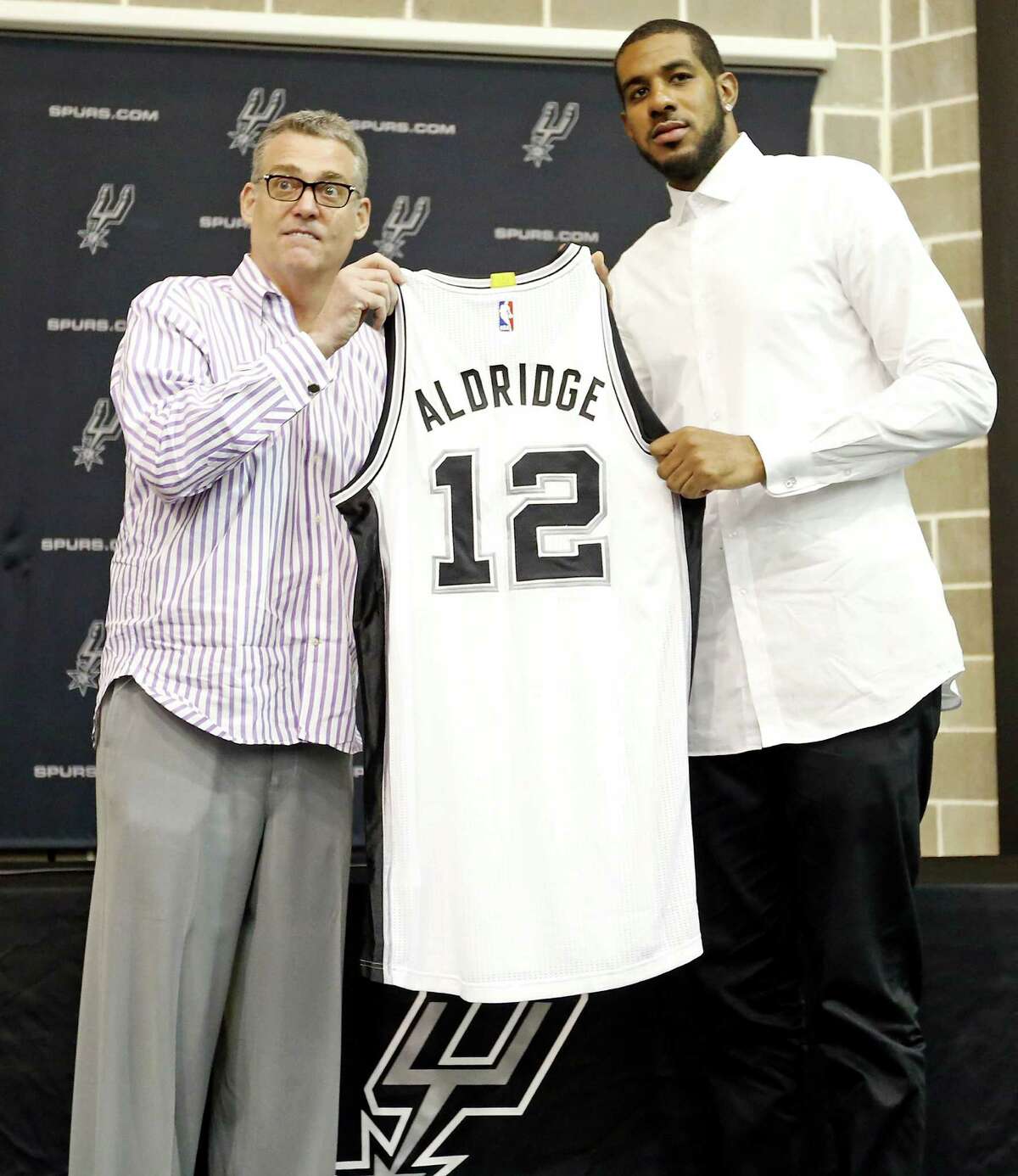 San Antonio Spurs general manager R.C. Buford (left), and LaMarcus Aldridge pose for photos with Aldridge's jersey during a press conference at the Spurs practice facility Friday July 10, 2015 where he was officially introduced.