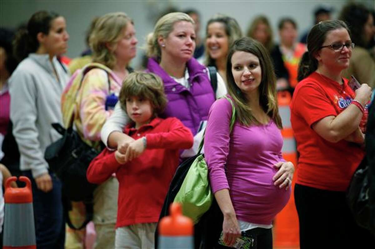 FILE - In this Thursday, Oct. 29, 2009 file photo, Nicole Andreacchio, second right, who is seven months pregnant waits in line to receive the swine flu vaccine from the Montgomery County Health Department at Congregation Beth Or in Maple Glen, Pa. A large study released by the New England Journal of Medicine on Wednesday, Jan. 16, 2013 offers reassuring news for pregnant women worried about getting a flu shot. The research found no evidence that the vaccine increases the risk of losing a fetus, and may prevent some fetal deaths. (AP Photo/Matt Rourke)