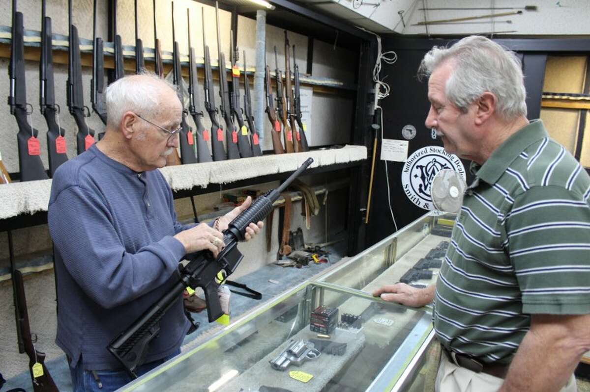 (File Photo) Tommy "Hoss Fly" Atchison, owner of Guns & Trades Inc., shows a DPMS AR-15 semi-automatic rifle to Midlander Aubrey Glosson Monday at his shop. Tyler White/Reporter-Telegram