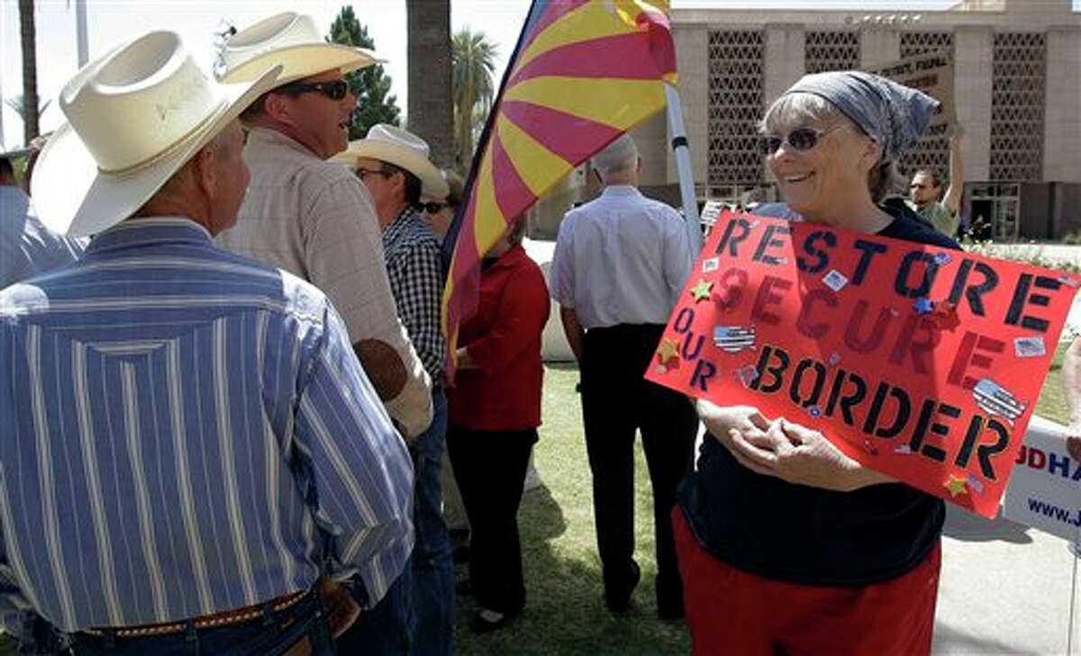 ADVANCE FOR USE MONDAY, FEB. 25, 2013 AND THEREAFTER - FILE - In this April 13, 2010 file photo, Ginger Niesen, right, talks with ranchers John Ladd, left, and Ban Bell as they join other ranchers, state legislators and protestors at the Arizona Capitol in Phoenix following the shooting death of Arizona rancher Robert Krentz. Krentz was gunned down while checking water lines on his property near the border where ranchers scoff at the word "secure." (AP Photo/Ross D. Franklin)