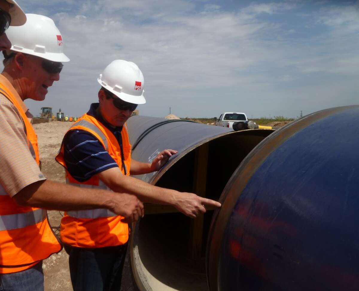 Mayor Wes Perry and Jay Edwards, general manager for Midland County Freshwater District #1, look over a section of the pipe that will carry water and how the pipe will ft together during a tour pipeline construction in Ector County Thursday afternoon. Photo by Kathleen Petty
