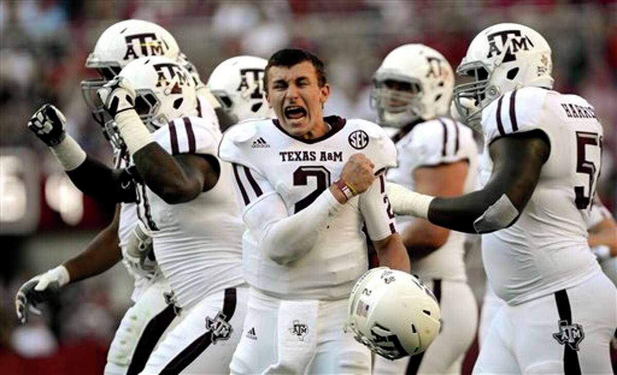 FILE - In this Nov. 10, 2012 file photo, Texas A&M quarterback Johnny Manziel (2) celebrates after a review proves an Aggie touchdown during the first half of an NCAA college football game against Alabama in Tuscaloosa, Ala. ESPN says the NCAA is investigating whether Manziel was paid for signing hundreds of autographs in January. Citing unidentified sources, ESPN's "Outside the Lines" said the Heisman Trophy winner signed items in exchange for a five-figure fee during his trip to Miami for the BCS championship game. (AP Photo/The Decatur Daily, Gary Cosby Jr., File)