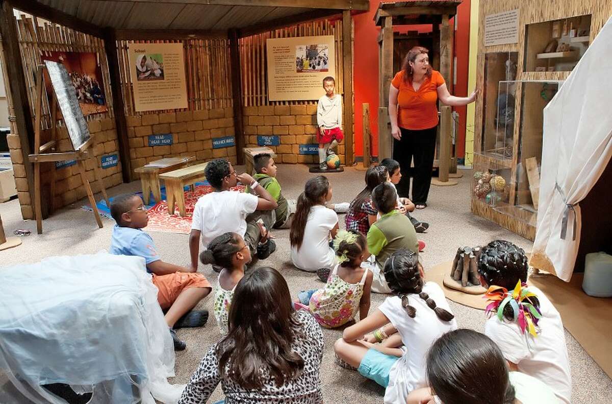 Annelorre Robertson talks to a group of Casa De Amigos students about the toys that were made by children in a refugee camp during a guided tour of the "Torn from Home, A Life as a Refugee" exhibit at the Museum of the Southwest children’s museum. Cindeka Nealy/Reporter-Telegram
