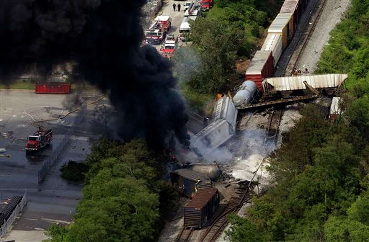 FILE- In this Tuesday, May 28, 2013, file photo, a fire burns at the site of a CSX freight train derailment, in Rosedale, Md., where fire officials say the train crashed into a trash truck, causing an explosion that rattled homes at least a half-mile away and collapsed nearby buildings, setting them on fire. The nation’s railroads are safer than ever, despite recent high-profile accidents like this week’s fiery derailment in Maryland. Derailments and crossing accidents have steadily declined nationwide even as businesses have come to increasingly rely on trains to move their raw materials and products. (AP Photo/Patrick Semansky)