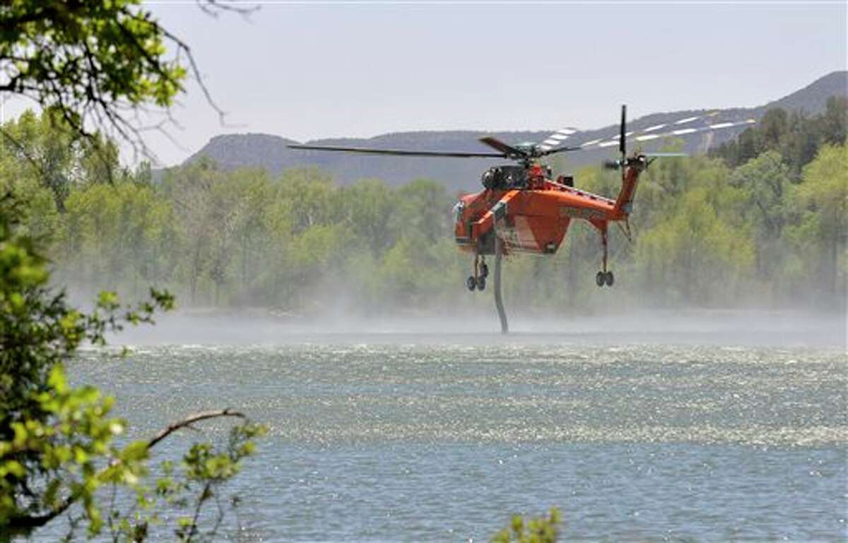 A helicopter hovers over Monastery Lake as it takes on a load of water, Saturday, June 1, 2013 near Pecos, N.M. Fire crews in New Mexico on Saturday fought two growing wild blazes that have scorched thousands of acres, spurred evacuation calls for dozens of homes and poured smoke into the touristy state capital. (AP Photo/The Albuquerque Journal, Eddie Moore) SANTA FE NEW MEXICAN OUT