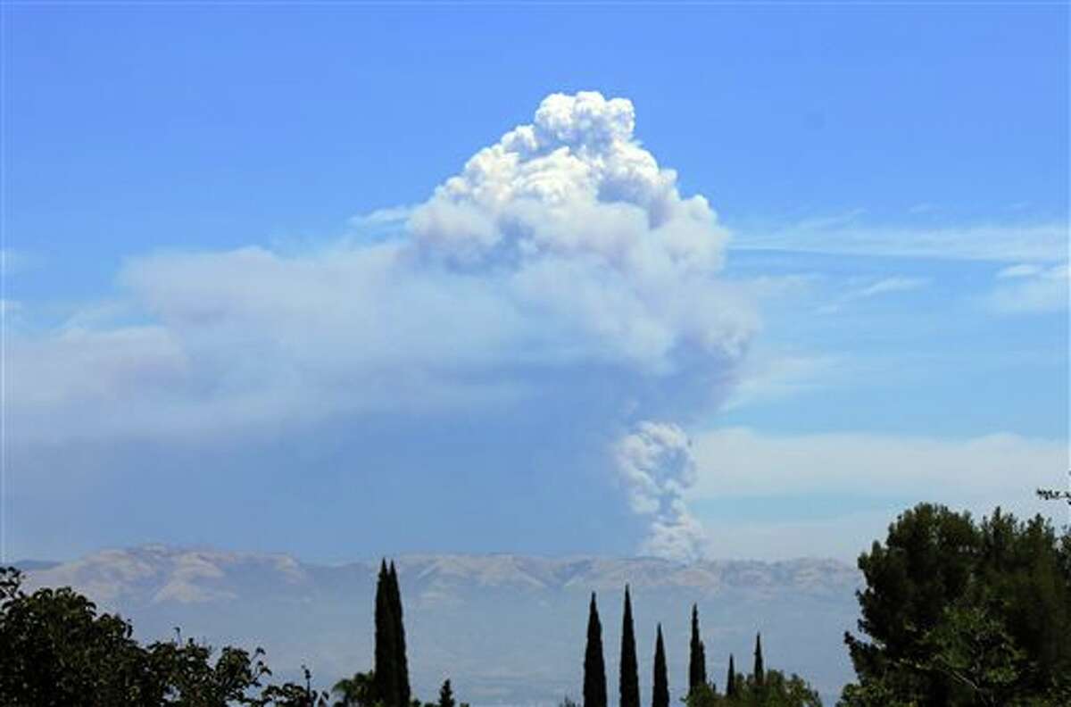 The Powerhouse Fire burning in the Angeles National Forest northwest of Los Angeles sends up a huge plume of smoke on Saturday, June 1, 2013. Smoke from the fire made visibility hazy in the San Fernando Valley, foreground. The blaze has burned thousands of acres of brush since it erupted Thursday afternoon near a utility powerhouse. (AP Photo/John Antczak)