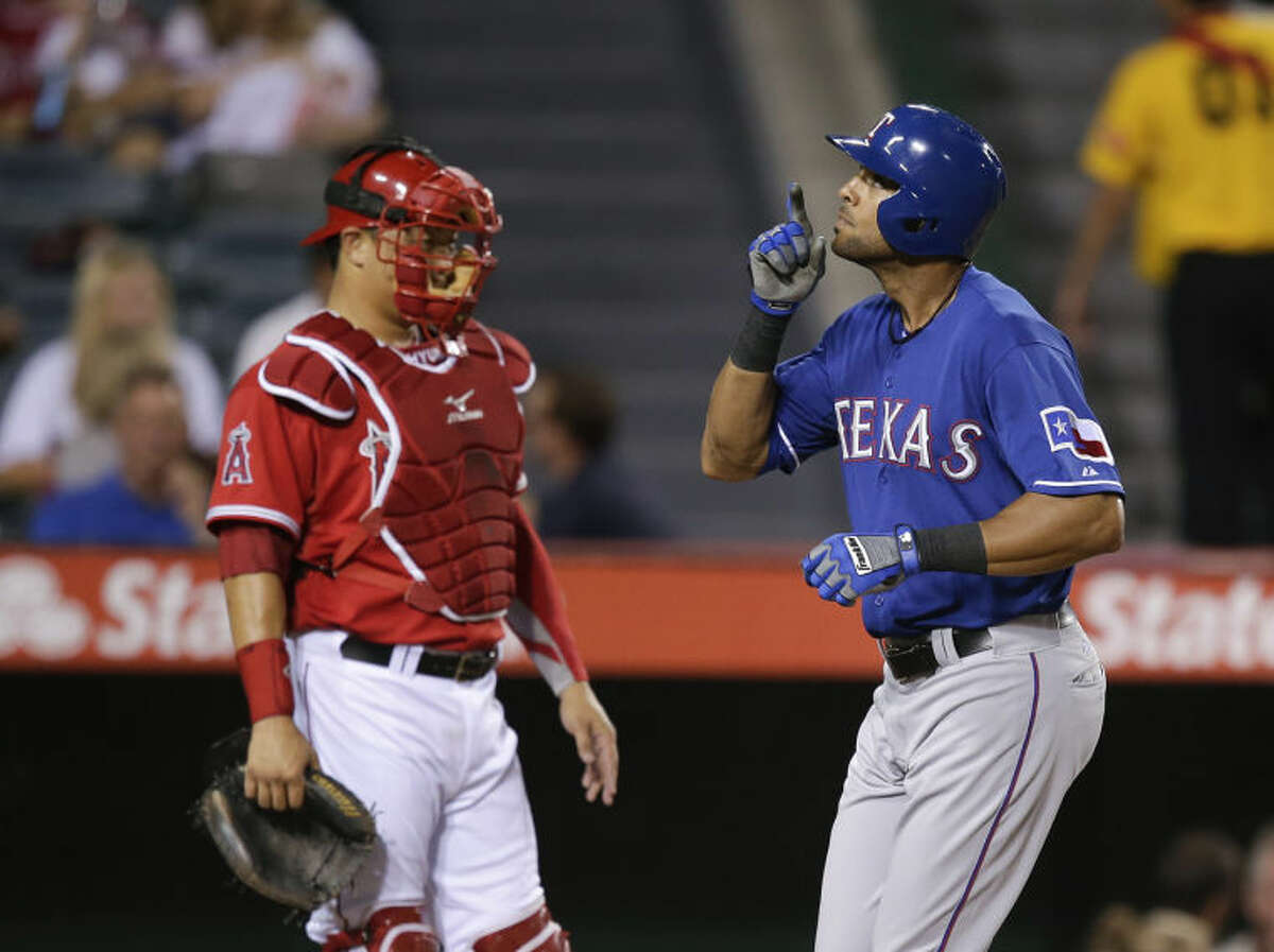 Texas Rangers' Alex Rios, right, celebrates his home run as he takes home plate past Los Angeles Angels catcher Hank Conger on Friday in Anaheim, Calif. (AP Photo/Jae C. Hong)