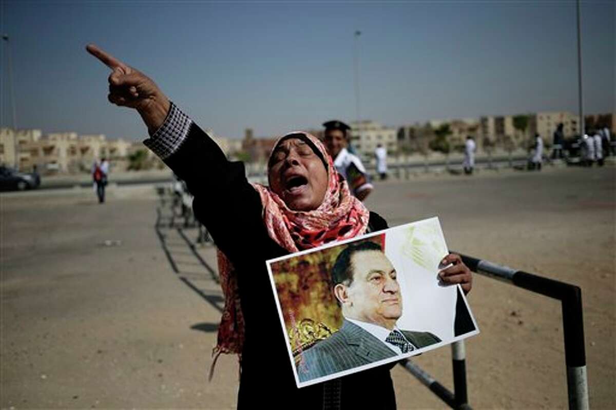An Egyptian woman carrying a photo of ousted president Hosni Mubarak chants slogans against ousted President Mohammed Morsi and the Muslim Brotherhood as she expresses her support for Mubarak at a court in Cairo, Egypt, Saturday, Sept. 14, 2013. The ousted long-time autocrat went back in court as his trial resumed on charges related to the killings of some 900 protesters during the 2011 uprising that led to his ouster. (AP Photo/Hassan Ammar)