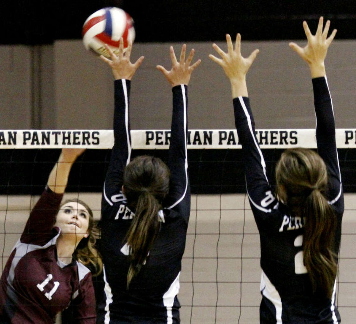 Midland Lee Bentleigh Dunavan spikes the ball against Permian defenders in the third set of the match Tuesday at the Permian Fieldhouse.