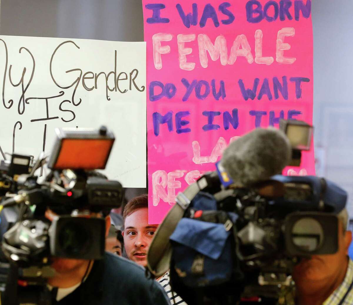 Protestors hold up signs to the window outside a room where Lt. Gov. Dan Patrick addresses the media on Fort Worth Superintendent Kent Scribner's policy to allow transgender students comfortable access to bathrooms. The press conference held before the school board meeting was at the Fort Worth ISD Board of Education complex in Fort Worth, Tuesday, May 10, 2016. (Tom Fox/The Dallas Morning News)