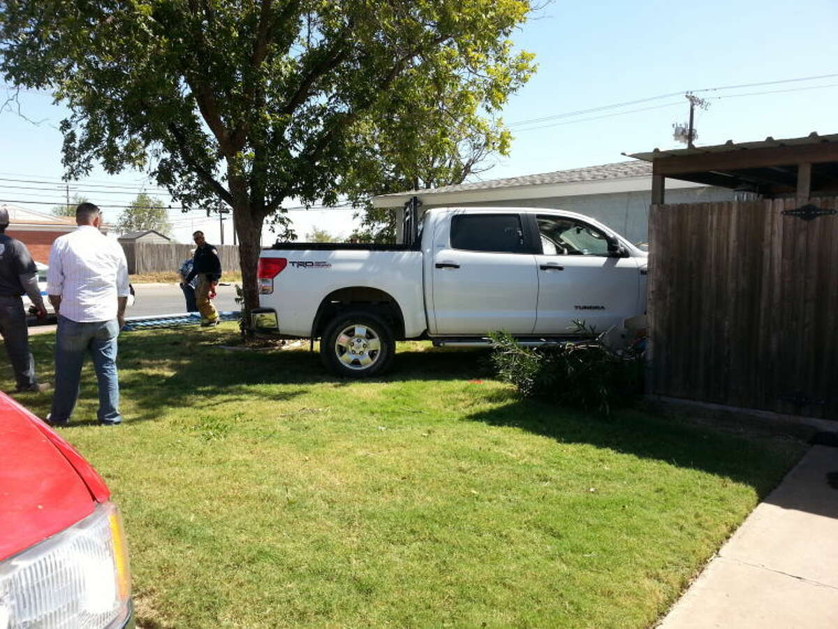 A wrecker removes a pickup from the fenced-in patio area of a southwest Midland home Saturday at about 1:30 p.m. The pickup veered across the property after nearly colliding with another driver who ran a stop sign at the intersection of Anetta and Midland drives.