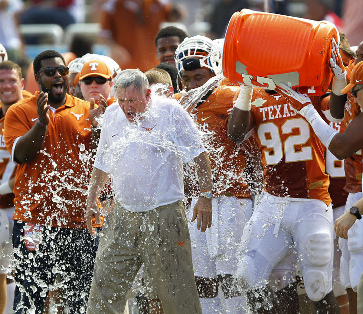 Texas head coach Mack Brown is doused with the water cooler by his players in the closing seconds of their 36-20 win over Oklahoma in an NCAA college football game at the Cotton Bowl in Dallas, Saturday, Oct. 12, 2013. (AP Photo/The Dallas Morning News, Tom Fox)